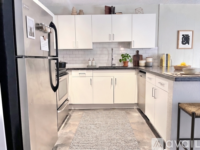 A kitchen with white cabinets and a stainless steel refrigerator.