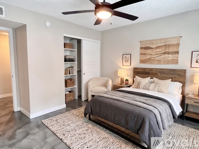 A bedroom with a bed, chair, and ceiling fan.