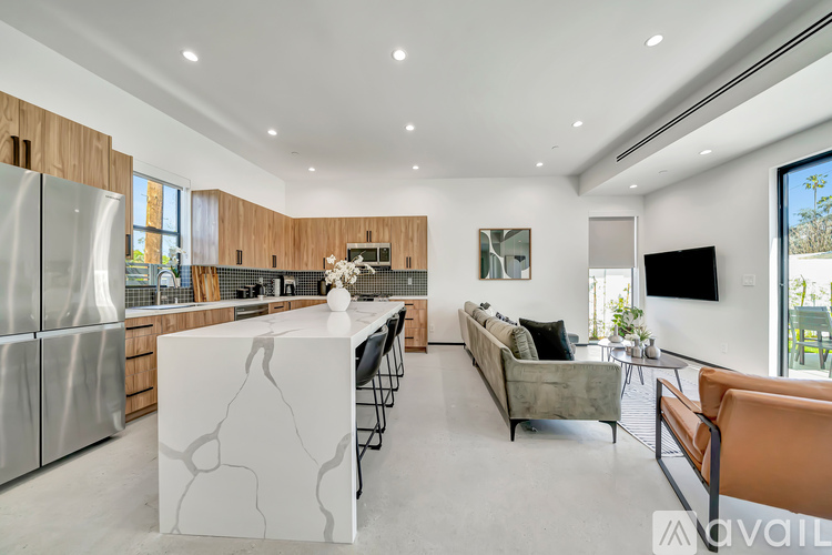 A modern kitchen with a marble island and a living room with a couch and a TV.