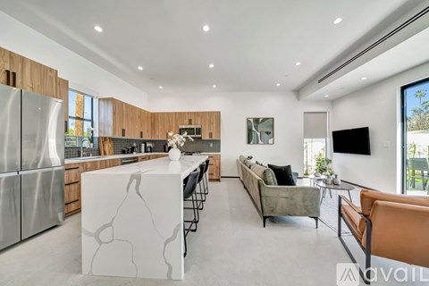 A modern kitchen with a marble island and a living room with a couch and a TV.