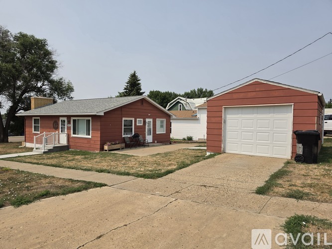 A red house with a white garage door is situated in a residential area.