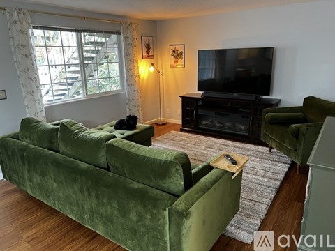 A living room with green velvet sofas and a television.