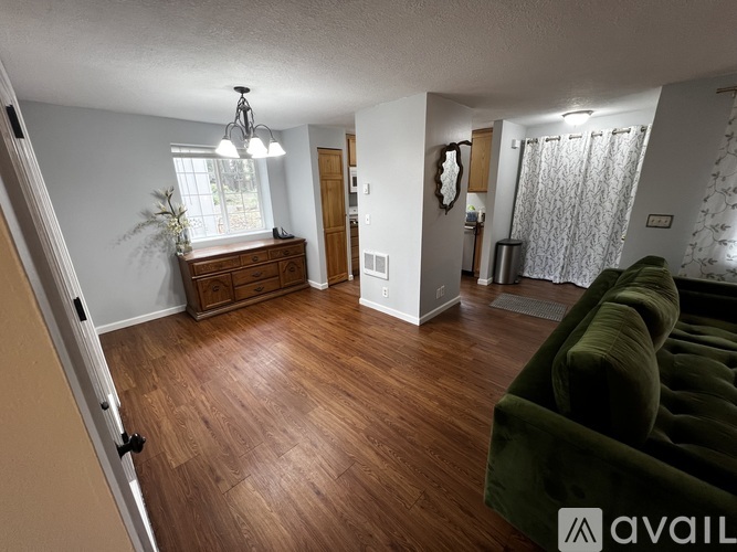 A living room with a green couch and wooden floors.