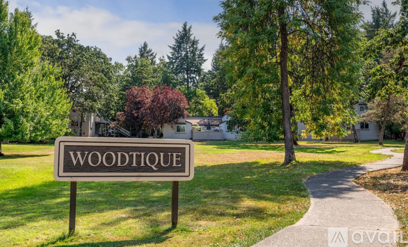 A sign that says "WOODTIQUE" stands in a grassy area.