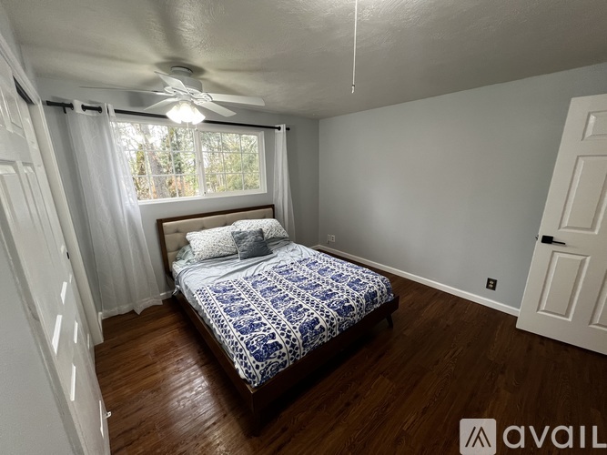 A bedroom with a bed, a ceiling fan, and a window with curtains.