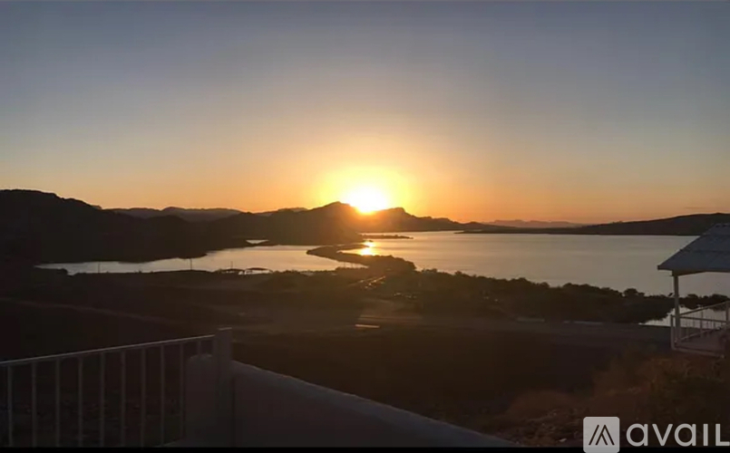 A sunset view from a balcony with the sun setting over a body of water.