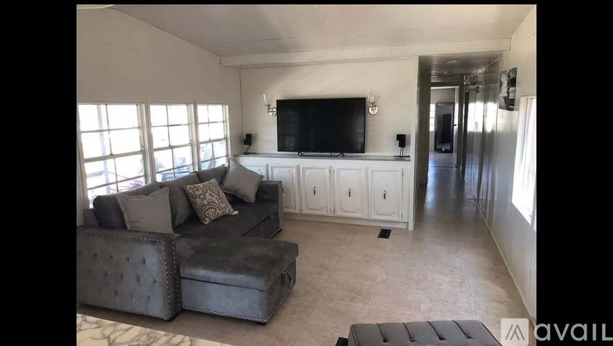 A living room with a grey couch and a television mounted on the wall.