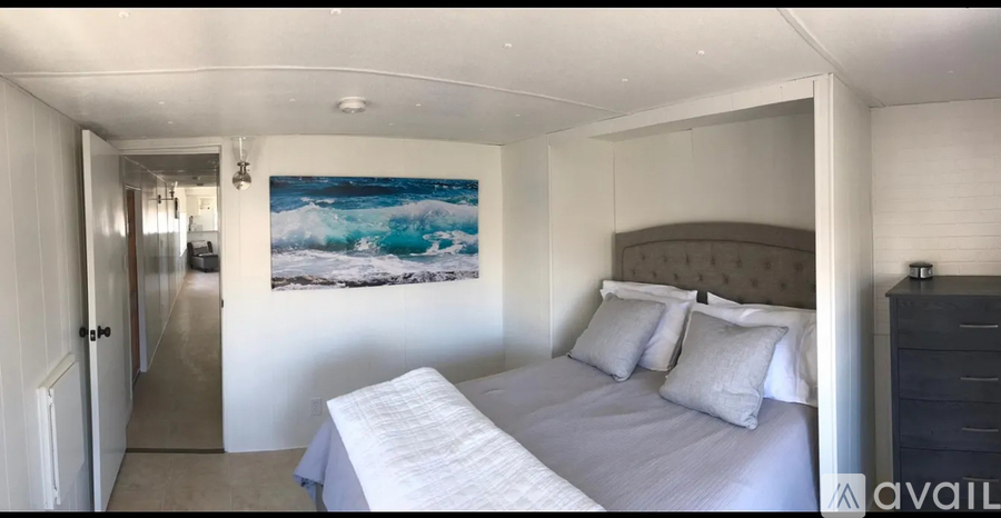 A bedroom with a large bed and a painting of a wave on the wall.