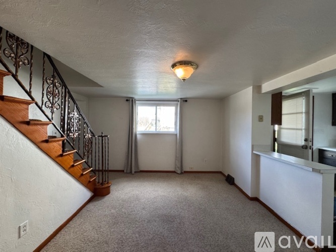 A spacious room with a staircase and a window.