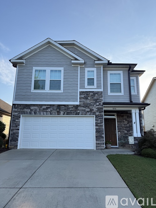 A two-story house with a garage door and a driveway.