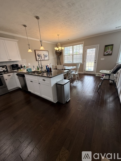 A kitchen with white cabinets and a wooden floor.