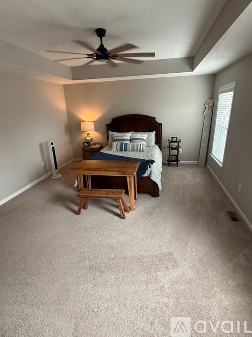 A bedroom with a bed, nightstand, and a fan.