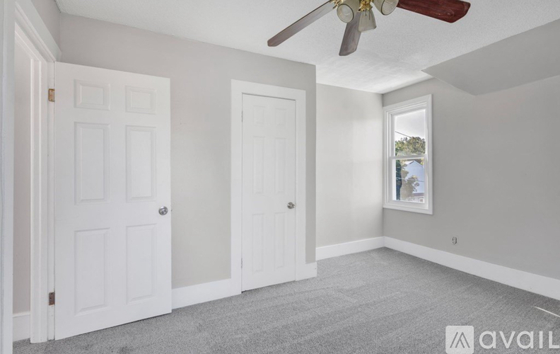 A room with two doors and a ceiling fan.