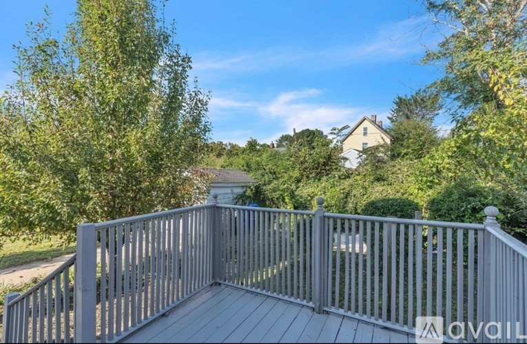 A deck with a railing overlooking a yard with a house in the background.