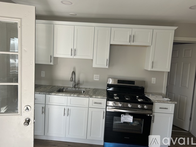 A kitchen with white cabinets and a black stove top oven.