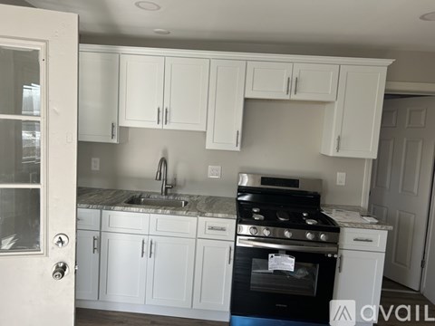 A kitchen with white cabinets and a black stove top oven.