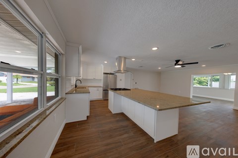A kitchen with white cabinets and a wooden countertop is available for rent.
