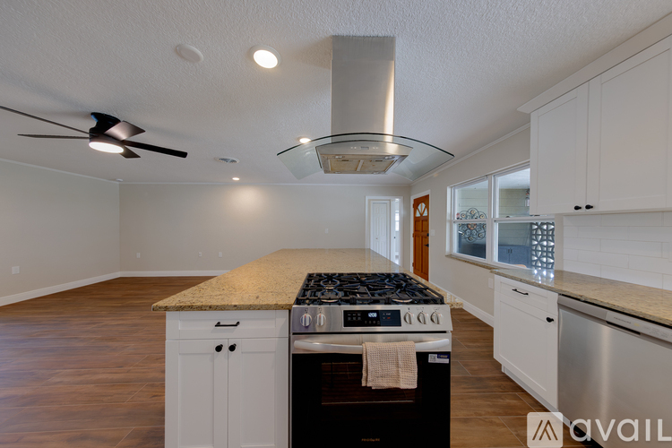 A kitchen with a stove top oven and a fan.