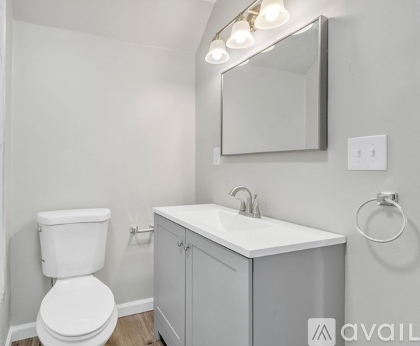 A bathroom with a toilet, sink, and mirror.
