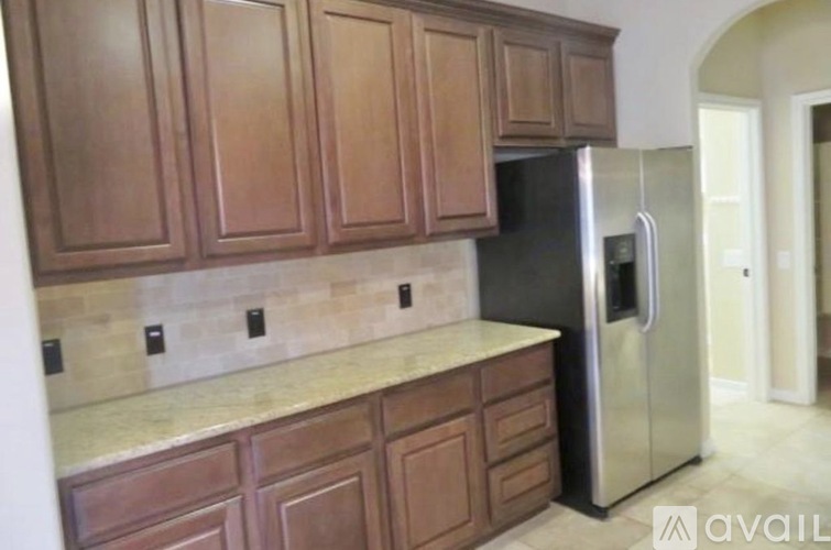 A kitchen with wooden cabinets and a black refrigerator.