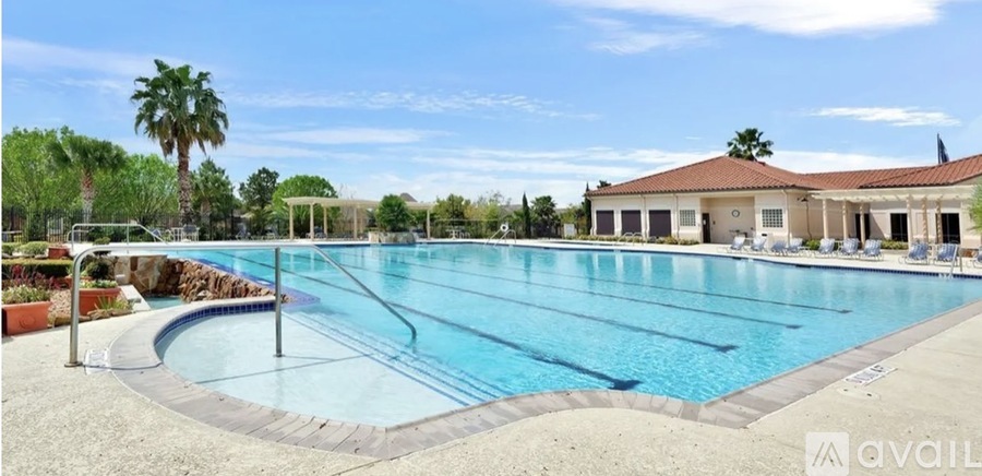 A large outdoor swimming pool with a separate kiddie pool and a building in the background.