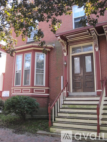 A red brick house with a white window and a brown door.