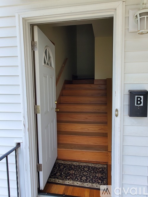 A white door with a black handle and a small black box on the wall.