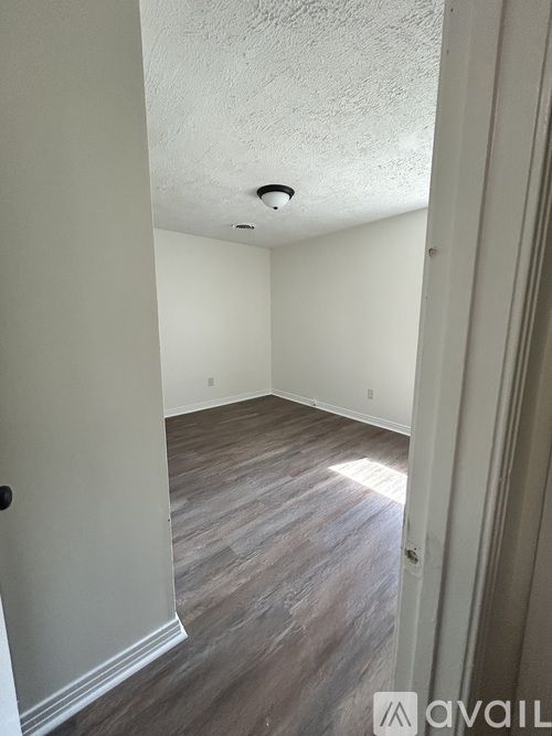 A room with wooden flooring and white walls.