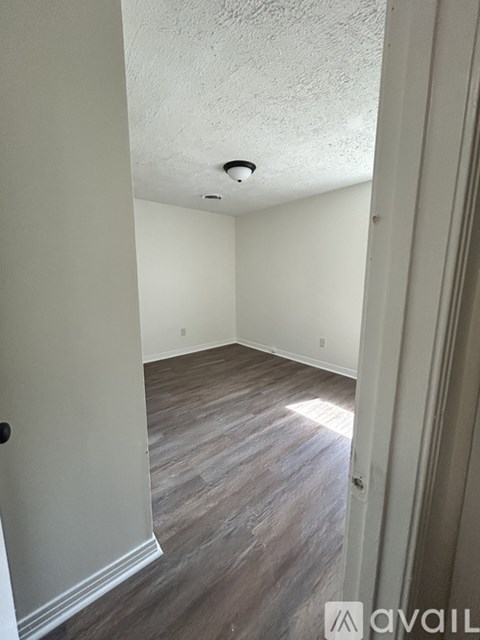 A room with wooden flooring and white walls.