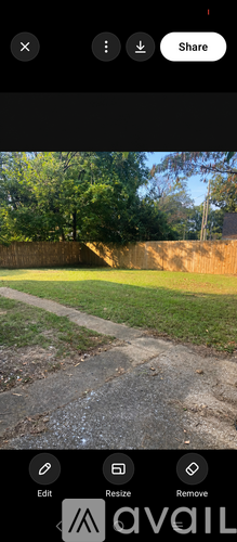 A pathway leads through a grassy area with a wooden fence in the background.