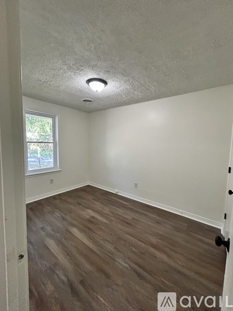A room with wooden flooring and a window.