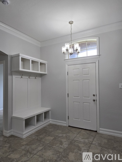 A white door is in a room with a chandelier.