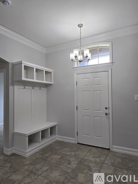 A white door is in a room with a chandelier.