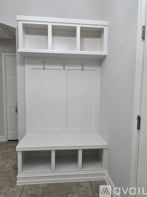 A white built-in bench and shelves in a room.