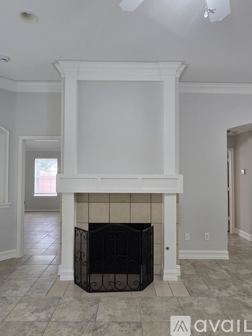 A white fireplace with a black grate in a room with white walls.