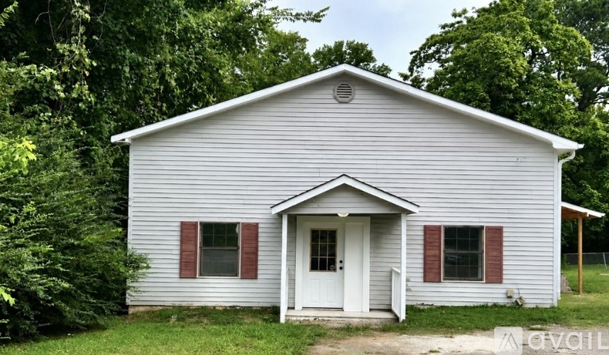A small white house with red shutters and a white door.