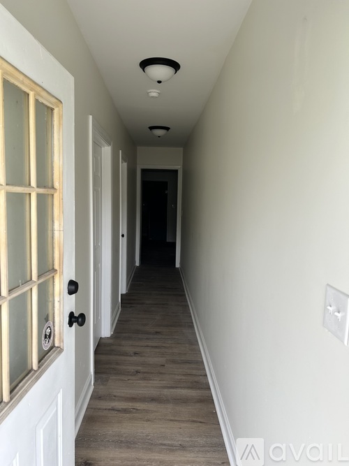 A long hallway with a door on the left and a light on the ceiling.