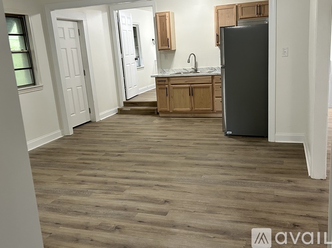 A kitchen with a refrigerator, sink, and cabinets.