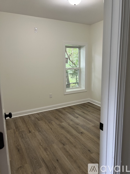 A room with a window and wood flooring.