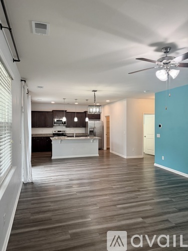 A spacious kitchen and living room with hardwood floors and a ceiling fan.