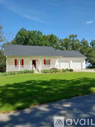 A white house with red shutters is for sale.