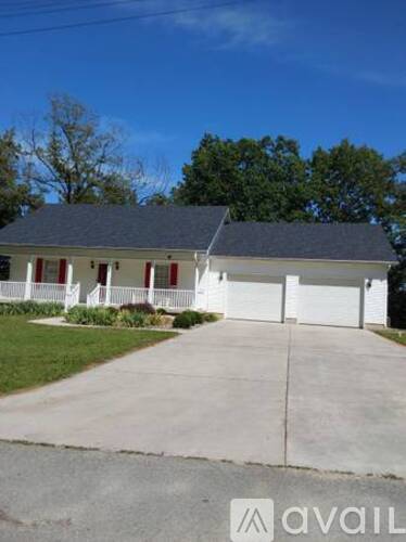 A house with a grey roof and white walls with a red door.
