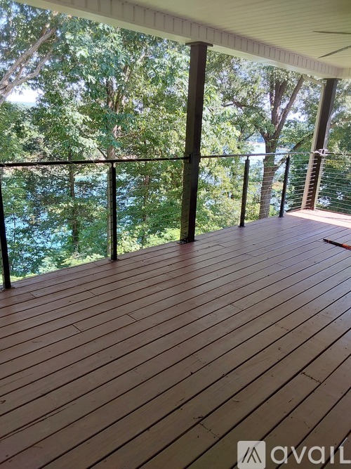 A wooden deck with a metal railing and trees in the background.