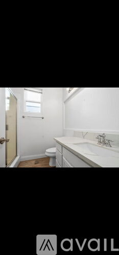 A bathroom with a toilet, sink, and a window.