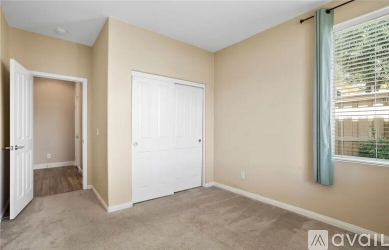 A room with a white door and a window with a view of a building.
