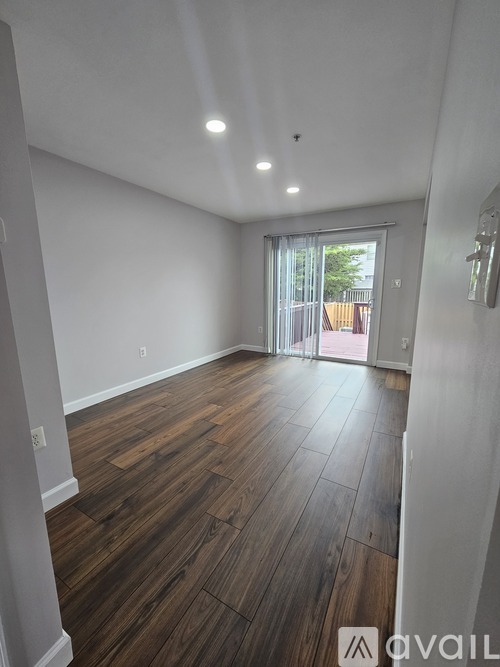 A room with wooden flooring and a sliding glass door leading outside.