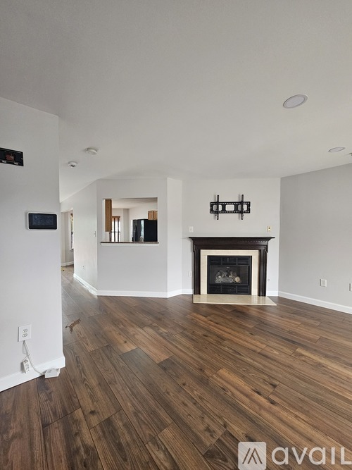 A living room with a fireplace and wood flooring.