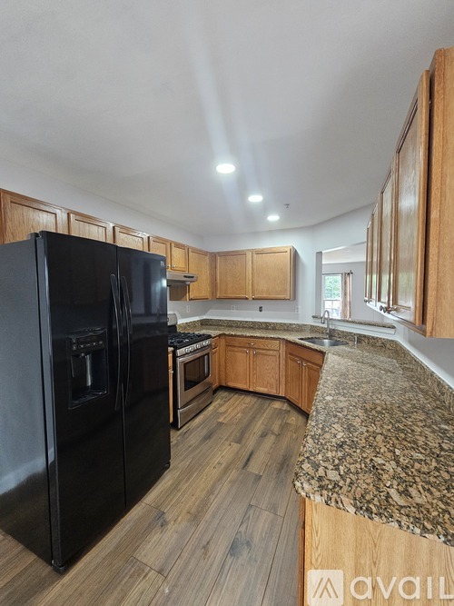 A kitchen with a black refrigerator and wooden cabinets.