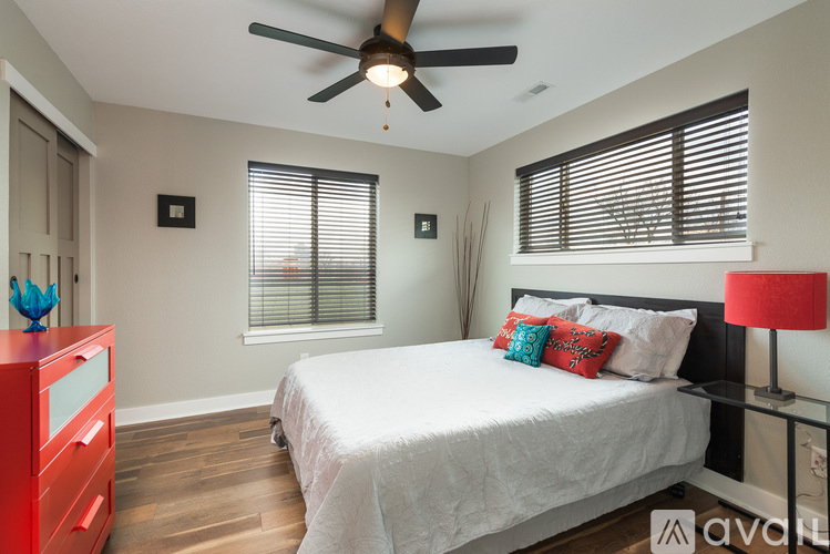 A bedroom with a white bed and a ceiling fan.