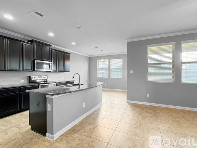 A kitchen with black cabinets and a stainless steel island.